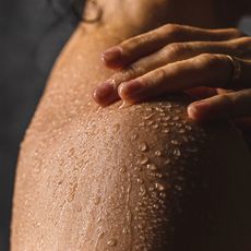 woman touching wet shoulder in the shower