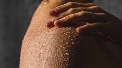 woman touching wet shoulder in the shower