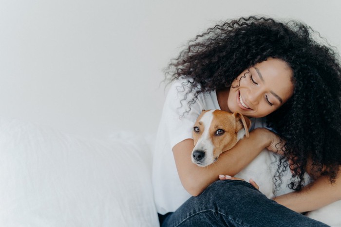 女性にハグされてストレスサインを出している犬