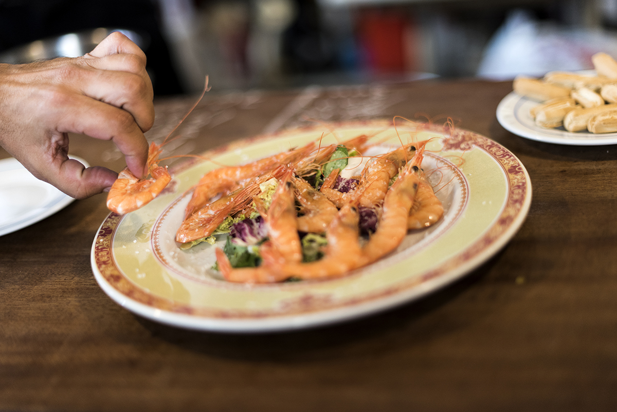 An unseen person takes a shrimp from a platter.