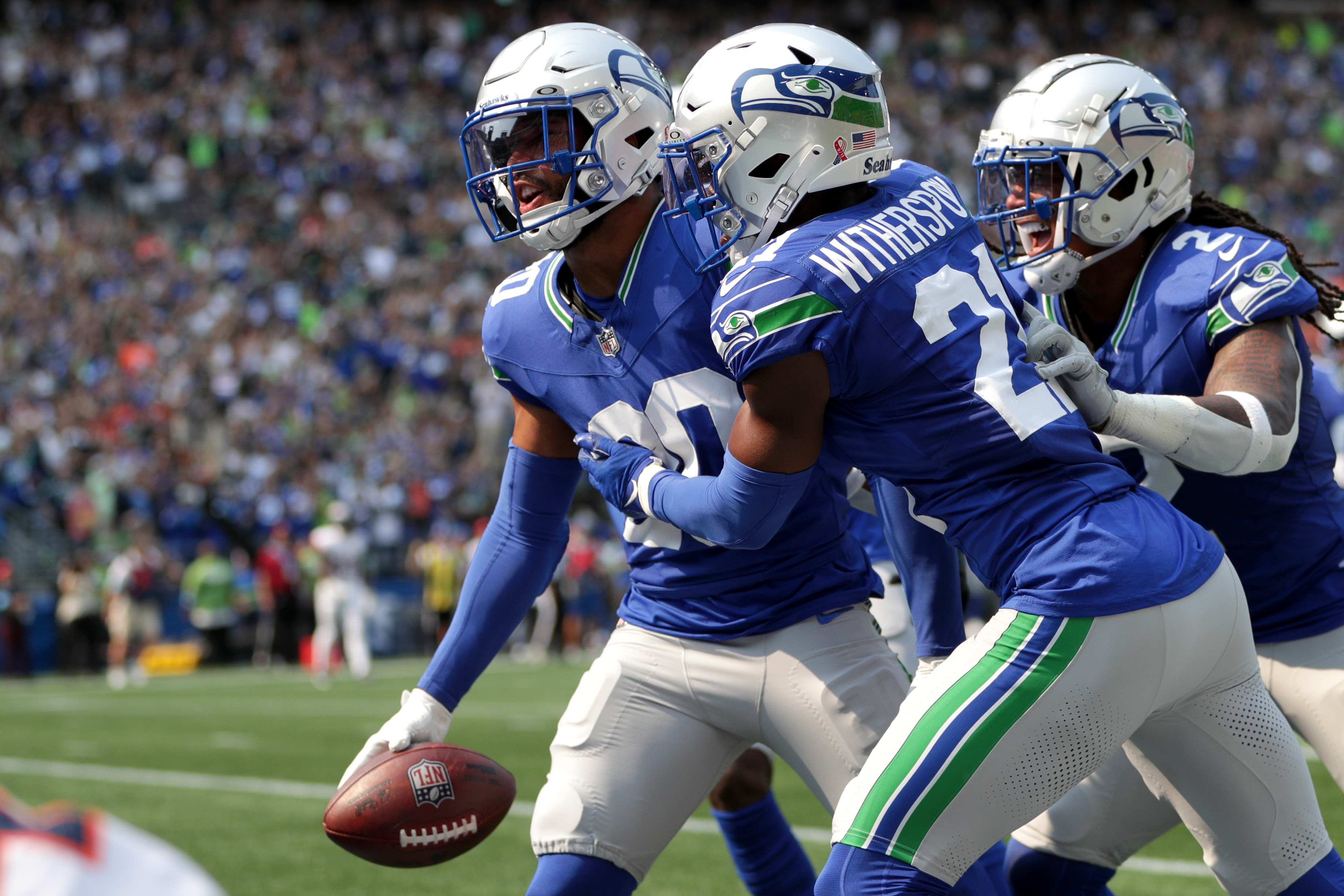 Julian Love #20, Devon Witherspoon #21 and Rayshawn Jenkins #2 of the Seattle Seahawks celebrate after Love’s interception during the second quarter against the Denver Broncos at Lumen Field on September 08, 2024 in Seattle, Washington.