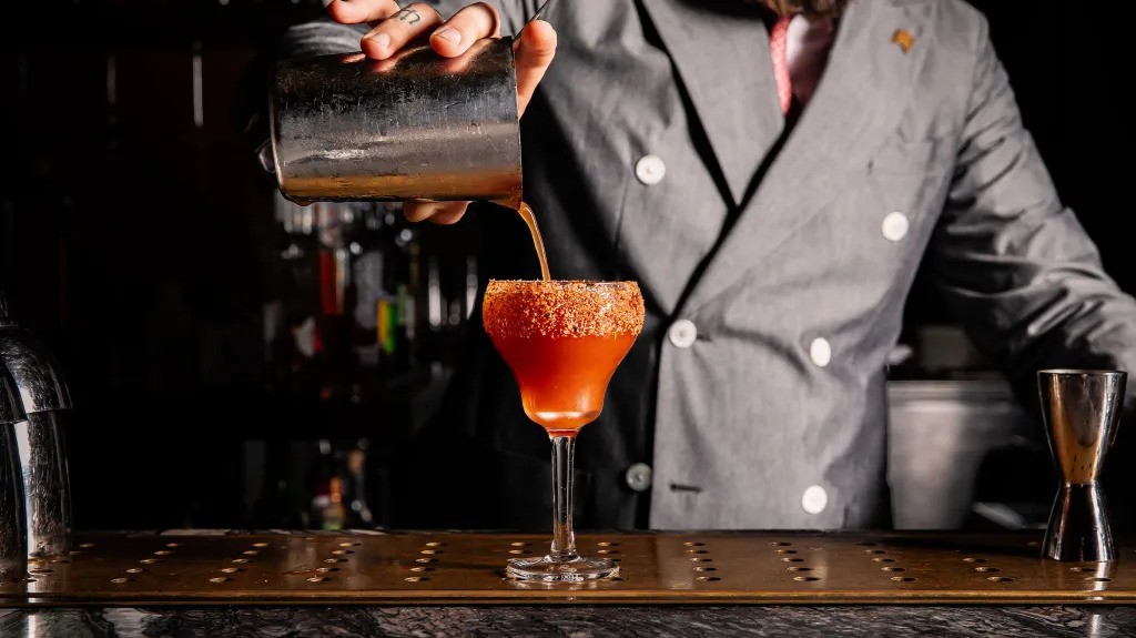 A bartender pours a bloody mary. 