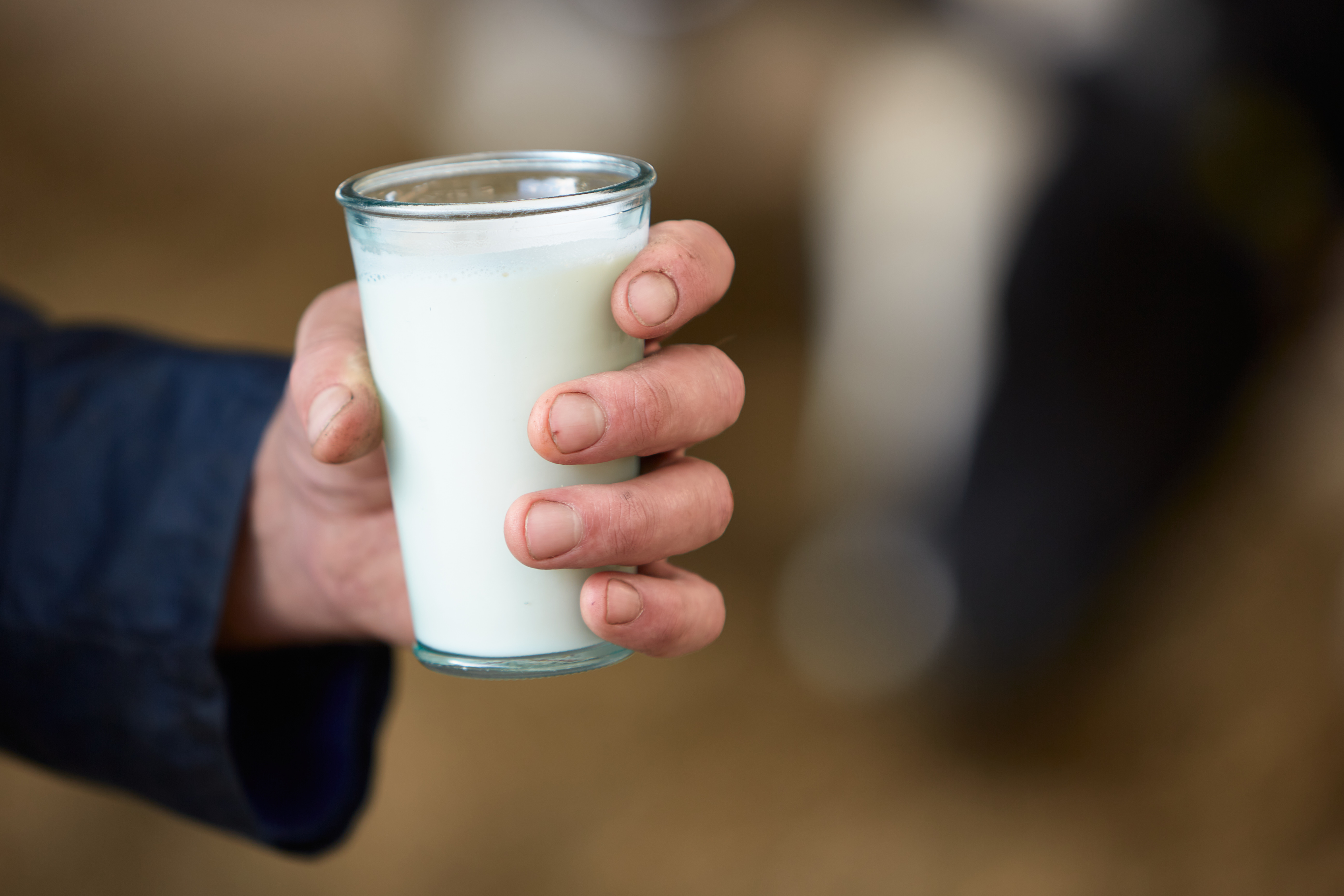 A hand holds a glass of milk.