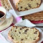 Slice of cake on a white plate with a cup of coffee.