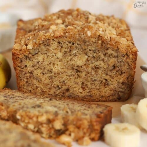 Loaf of banana nut bread cut open on a piece of parchment paper.