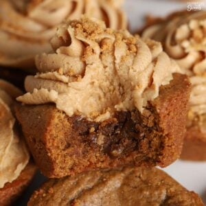 Gingerbread cookie cup topped with light brown frosting with a bite taken out of it.