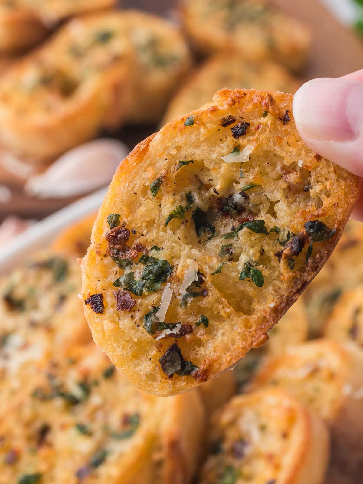 A hand holding up a slice of Air Fryer Garlic Bread.