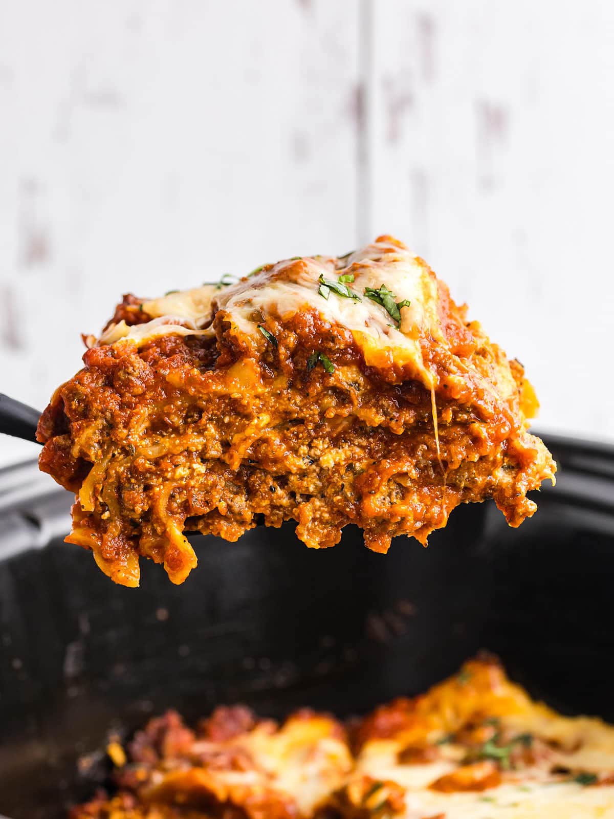 Closeup of a slice of Crockpot Lasagna being lifted out of the slow cooker.