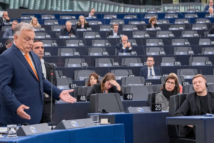 Baloldalt Orbán Viktor mond beszédet az Európai Parlamentben, Strasbourgban. Mögötte széksorokon képviselők ülnek szellősen.