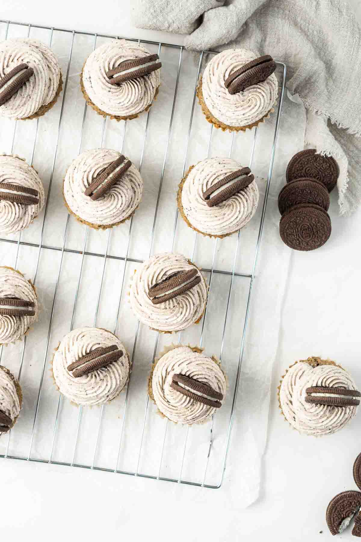 Oreo cupcakes frosted with buttercream from above on a wire rack.