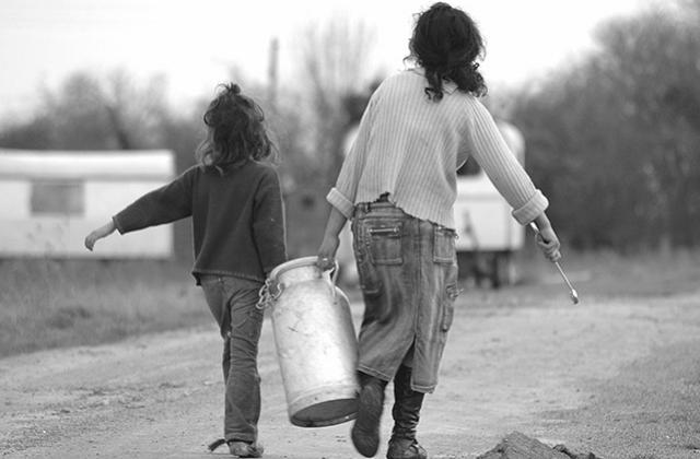 Two Traveller children carrying a container