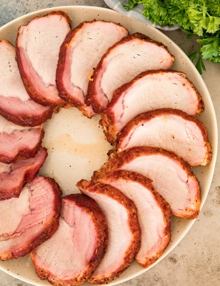 A plate with slices of smoked pork loin in a circle.