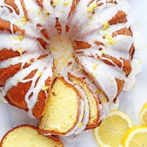 Lemon cake baked in bundt pan on the table slice slices cut and fresh lemons.