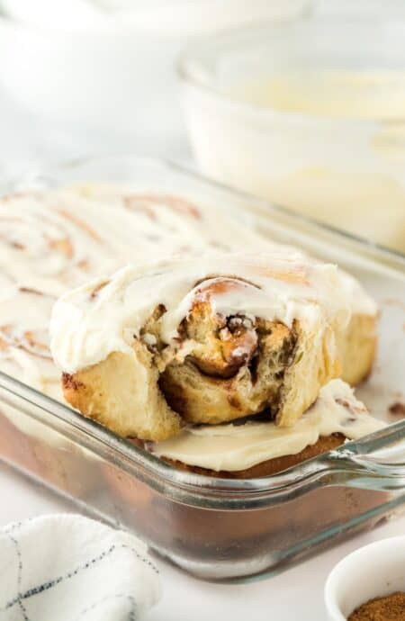 A side view of a homemade cinnamon roll with a bite taken out, highlighting the swirled cinnamon filling