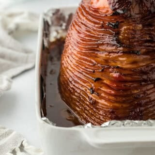 Perfectly roasted honey glazed ham recipe in foil in a white pan ready to enjoy