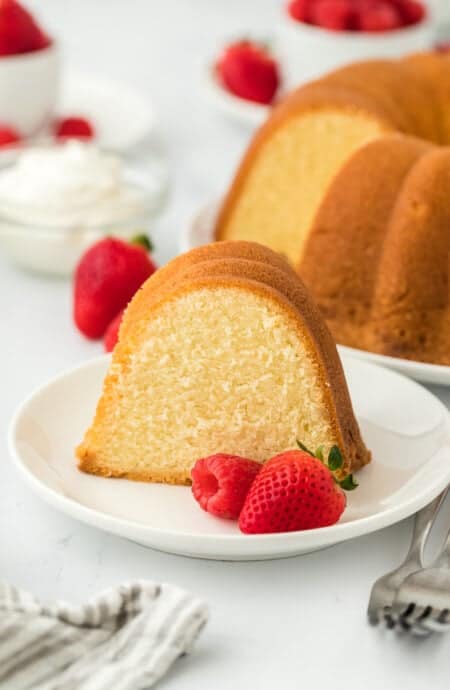 A slice of the best pound cake recipe on a white plate with berries to serve