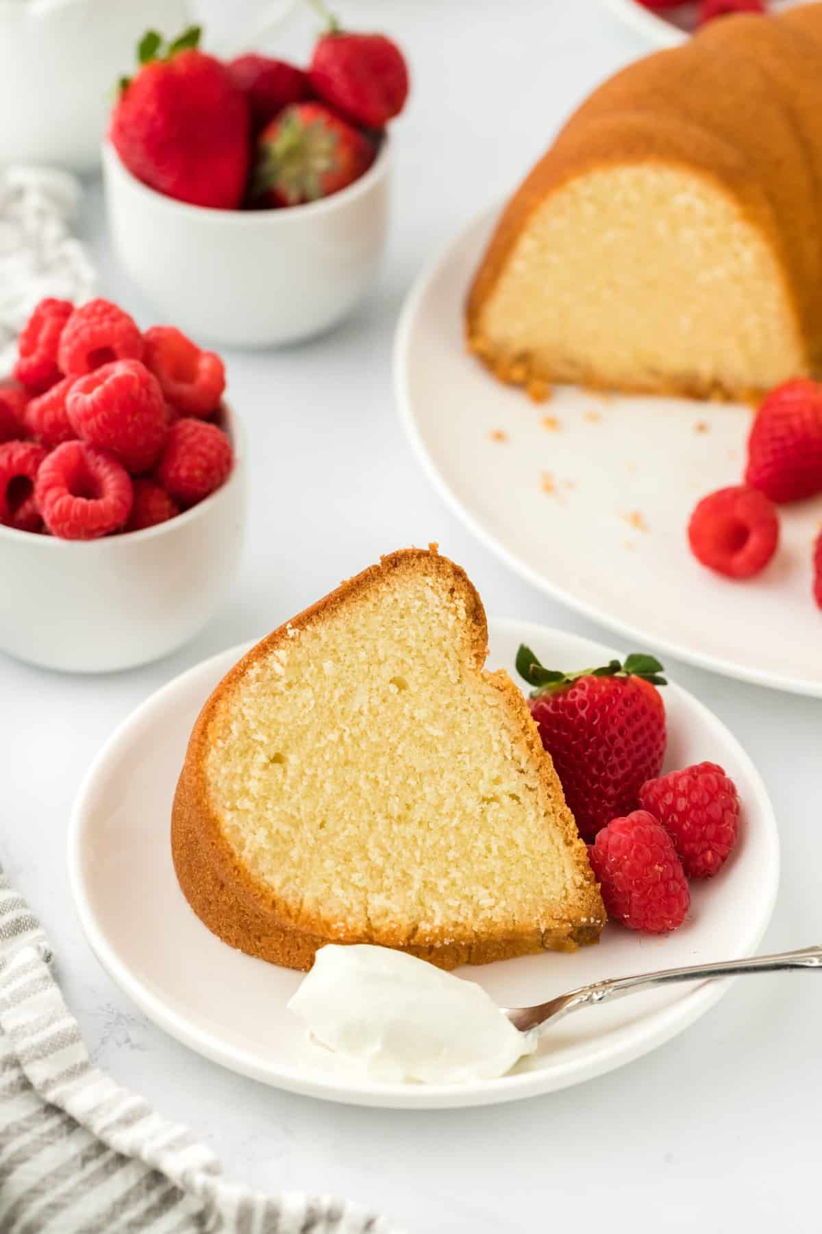 A slice of pound cake ready to enjoy on a white plate with whipped cream