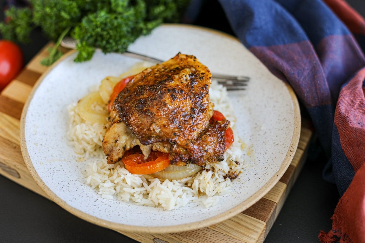 one baked chicken thigh on a plate.