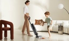 a person vacuums the floor while a child plays nearby