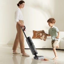 a person vacuums the floor while a child plays nearby