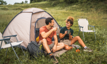 couple in love sit on the grass enjoy camp with coffee and talk