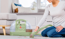 A person cleaning a carpet with the Bissell Little Green Machine