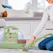 A person cleaning a carpet with the Bissell Little Green Machine