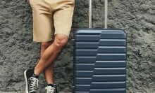 A man stands next to a suitcase