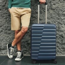 A man stands next to a suitcase