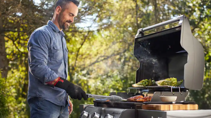 A man cooks out on a Weber grill