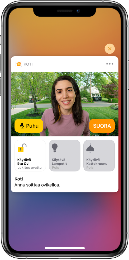 iPhonen näytössä on Koti-apilta tullut ilmoitus. Siinä näkyy etuovella olevan ihmisen kuva ja Puhu-painike vasemmalla. Alla ovat etuoven ja pihan valojen lisälaitepainikkeet. Lisälaitepainikkeiden alla näkyvät sanat ”Ashley soittaa ovikelloa”. Ilmoituksen oikeassa yläkulmassa on sulkemispainike.