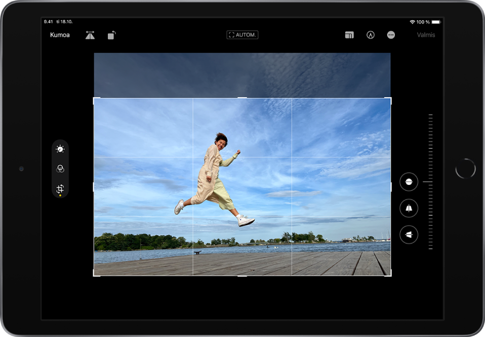 iPad vaakasuunnassa. Näytön keskellä on kuva Muokkaa-tilassa, ja kuvan päällä on ruudukko ja rajauskehys. Näytön vasemmalla puolella ovat Muokkaa-, Suodattimet- ja Rajaa-painikkeet. Rajaa-painike on valittuna. Näytön oikealla puolella ovat rajauksen parannusvalinnat ja voimakkuuden liukusäädin. Vasemmassa yläkulmassa ovat painikkeet Kumoa, Käännä ja Pyöritä. Oikeassa yläkulmassa ovat painikkeet Kuvasuhde, Merkintä ja Valmis.