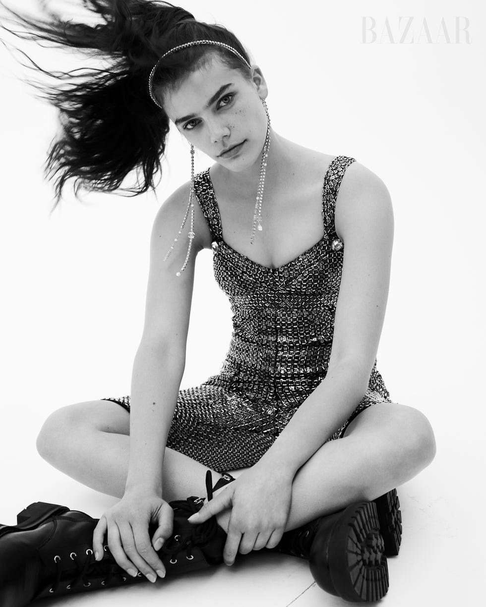 black and white photo of woman sitting in sequined romper and black boots