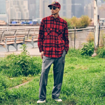 a person wearing a red plaid shirt and gray cargo pants stands in a green park area