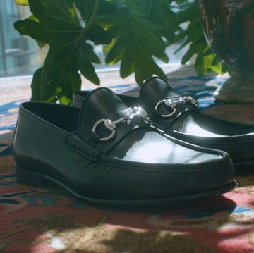 a pair of black shoes on a rug by a plant