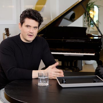 a couple of men sitting at a table with a piano in the background