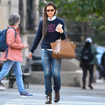 individual walking on a city street with a brown handbag