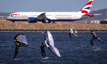 Wing surfers in the foreground and a plane in the background