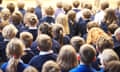 A group of children sitting down in a school hall during a educational assembly.