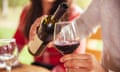 man pouring red wine into a glass