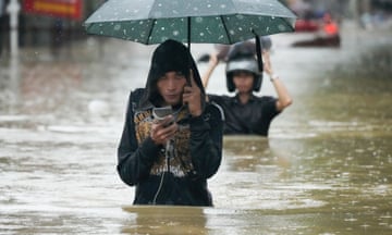 People wade through murky water that reaches above their waist