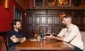 Two men sitting talking at a restaurant table in a pannelled room