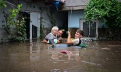 People in chest-high water outside a house in Romania