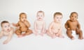 Five babies in nappies - one on its belly, four sitting - against a white background.