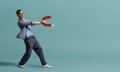 Tim Dowling leaning backwards, holding a giant magnet, against blue background