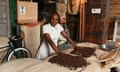 A woman smiles in front of piles of coffee beans in a warehouse.