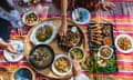 Group of Asian people family enjoy celebrating Thai food dinner while sitting on mat at home, Northeast thailand (Issan) healthy traditional Thai foods concept, Top view