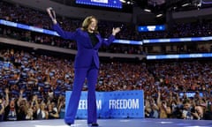 woman wearing blue suit holds up hands in crowded auditorium