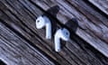 A pair of Apple AirPods 4 earbuds on a review table.