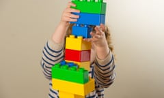 A preschool age child playing with plastic building blocks